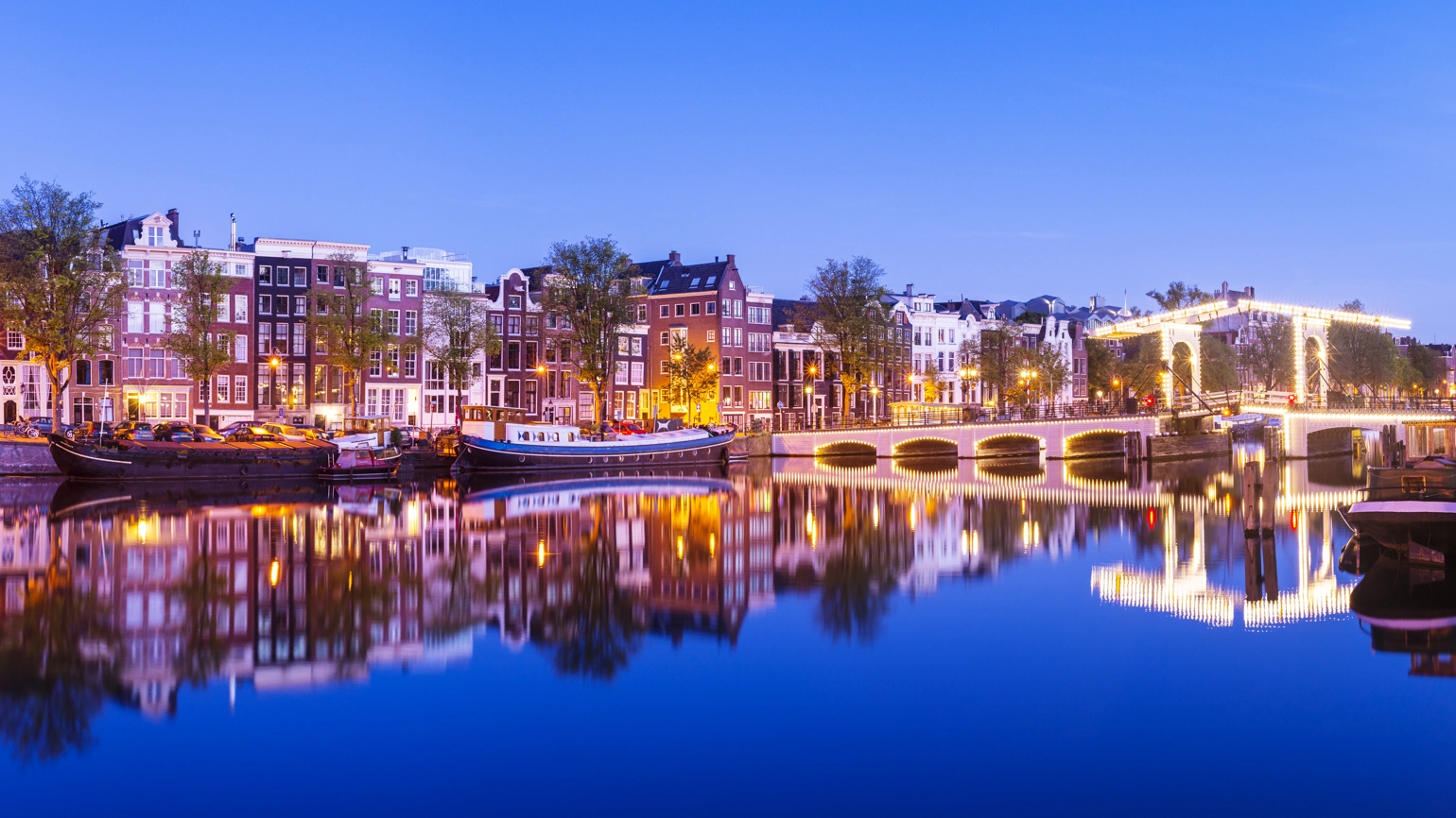 Magere Brug Bridge and canal houses on the Amstel River in Amsterdam, Netherlands, at twilight. Magere Brug Bridge and canal houses on the Amstel River in Amsterdam, Netherlands, at twilight.